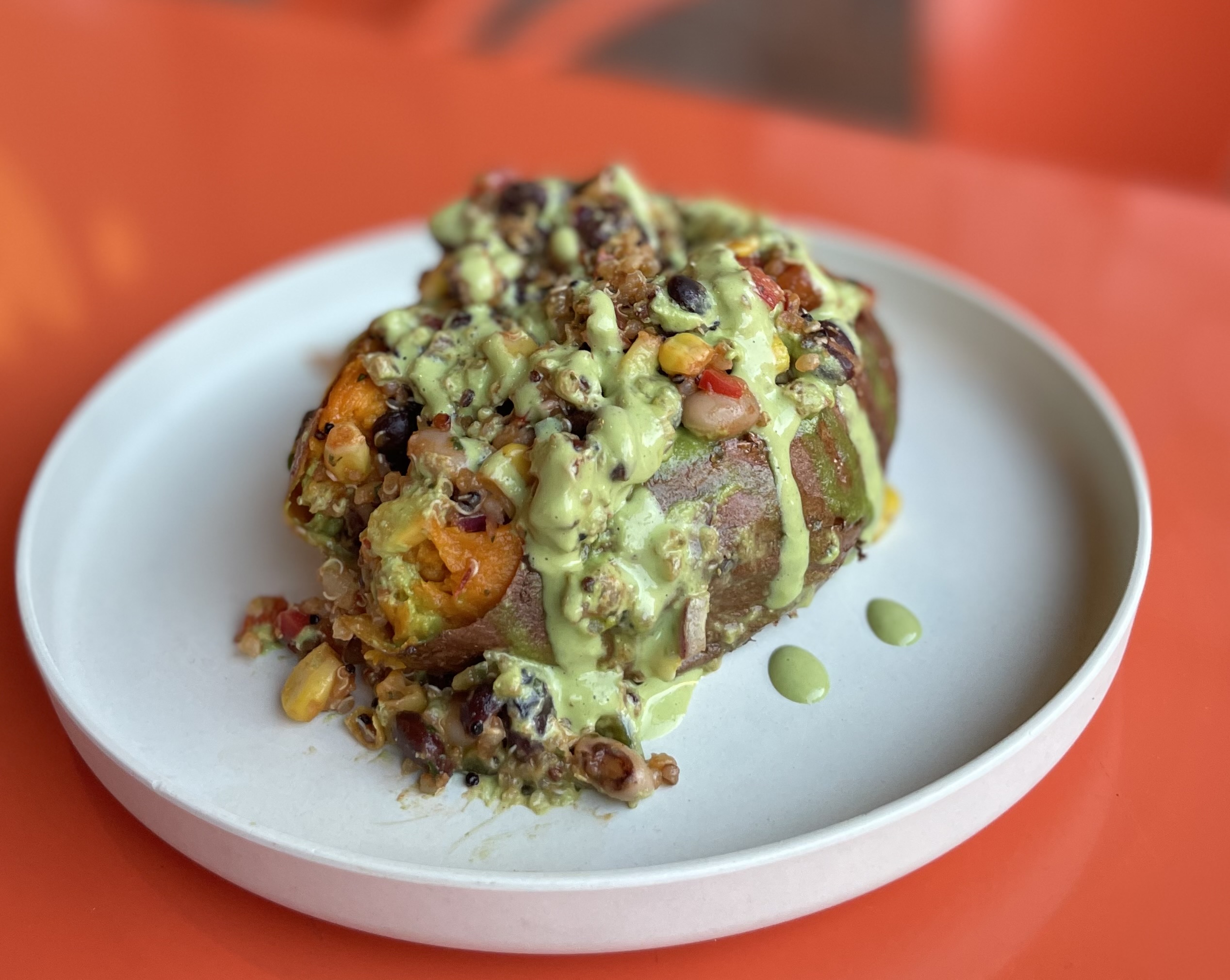 Cowboy sweet potato, baked and loaded with beans and plant-based toppings.